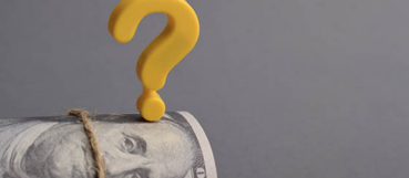 Question mark resting on a rolled dollar bill, representing nonprofit financial decision-making with guidance from a non profit CPA in Harford County.