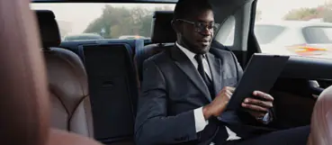 businessman in the backseat of a car working | tax preparation baltimore county | Weyrich, Cronin & Sorra