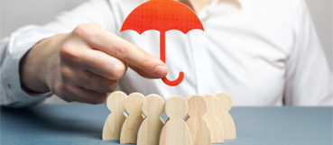 Hand holding a red umbrella over a group of wooden figures, representing D&O insurance for nonprofits with guidance from a CPA in Towson at Weyrich, Cronin & Sorra.