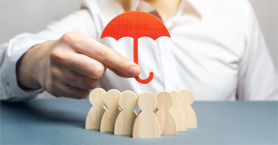 Hand holding a red umbrella over a group of wooden figures, representing D&O insurance for nonprofits with guidance from a CPA in Towson at Weyrich, Cronin & Sorra.