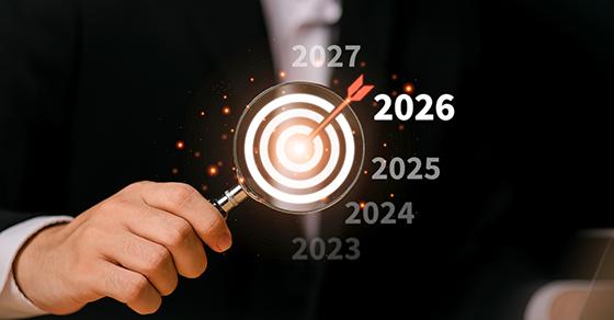 Hand holding a magnifying glass over a target with 2026 highlighted, representing year-end tax planning by Weyrich, Cronin & Sorra