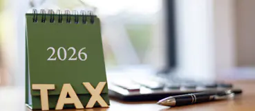 Green 2026 tax desk calendar next to a calculator and pen, representing year-end tax planning from Weyrich, Cronin & Sorra